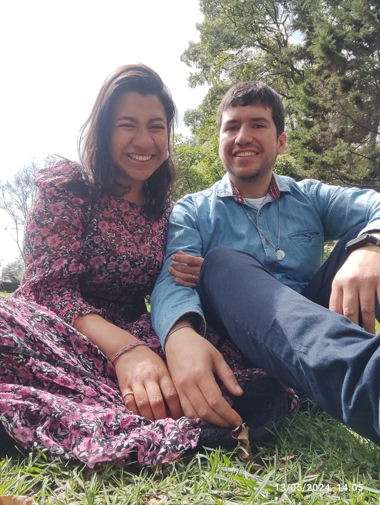 La pareja sentada junta sobre el césped.