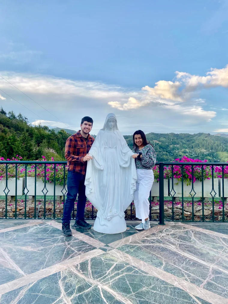 La pareja posando en un mirador rodeado de montañas.
