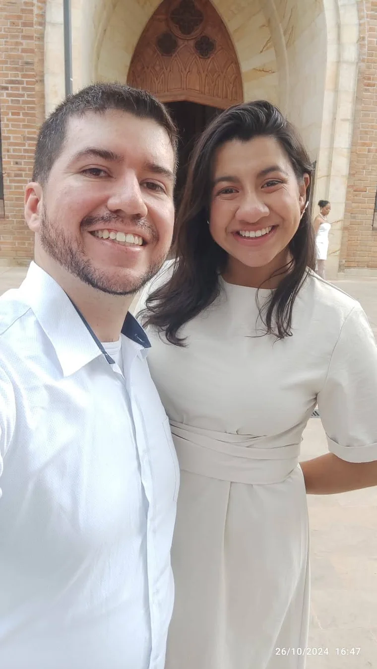 La pareja sonriendo frente a la entrada de una iglesia.